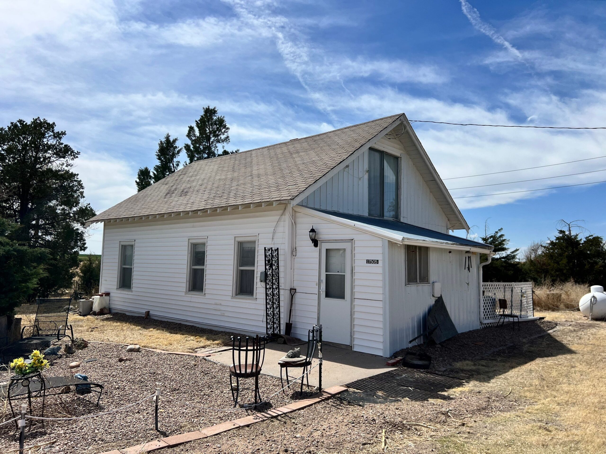 House with a sloped roof, white siding, and a porch, surrounded by a garden area, emphasizing residential storm damage restoration and inspection services.