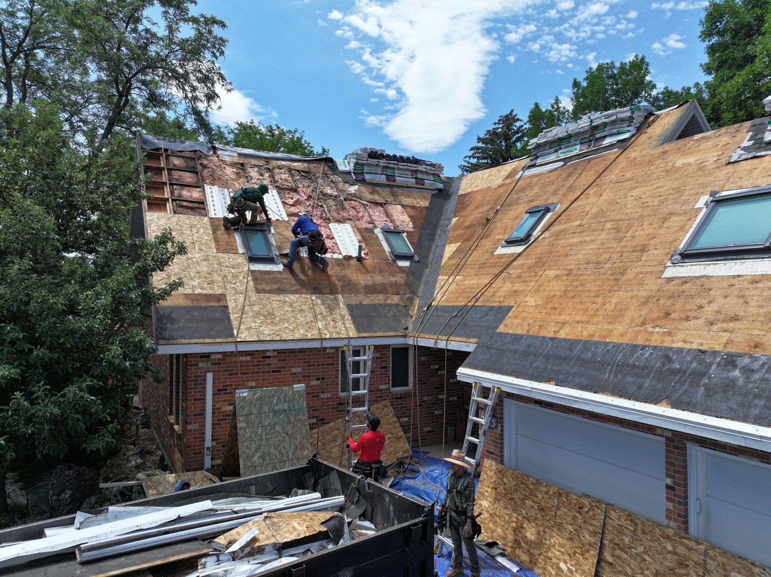 Roofing crew performing hail damage restoration on a residential property, with workers applying new materials on the roof and equipment scattered around the site.